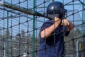 A young batter taking a swing in the batting cage