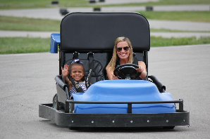A young driver waves from a yellow Kart Kountry go-kart